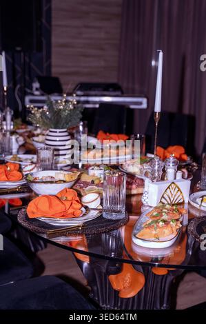 Tavolo da banchetto servito con tovaglioli d'arancia e antipasti gourmet all'interno di un ristorante. Concetto di catering professionale per eventi, ospitalità di lusso Foto Stock