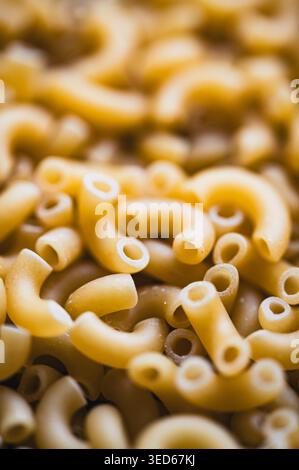 Primo piano di una grande quantità di pasta di macaroni crudi secchi. Foto Stock