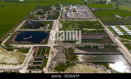 Una vista aerea ad alto angolo di un impianto di trattamento delle acque reflue situato in un'area rurale mostra i serbatoi e gli edifici. Foto Stock