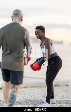 Donna sorridente e allenata a pugilato con la partner all'aperto Foto Stock