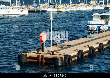 Porquerolles, Francia - 7 dicembre 2025: Molo portuale con attrezzature di sicurezza e posti di ormeggio circondato da barche a vela e yacht nel porto turistico sull'Ile de po Foto Stock