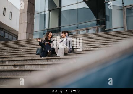 Due studenti delle scuole superiori seduti sui gradini del campus studiano e chiacchierano all'aperto Foto Stock