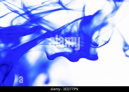Gocce di inchiostro blu astratto surreale che ondulano all'interno dell'acqua con sfondo bianco Foto Stock