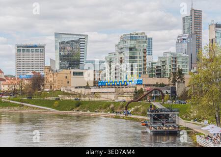 Barche lungo il fiume Neris, a Vilnius, Lituania, Europa con edifici moderni e grattacieli sullo sfondo Foto Stock
