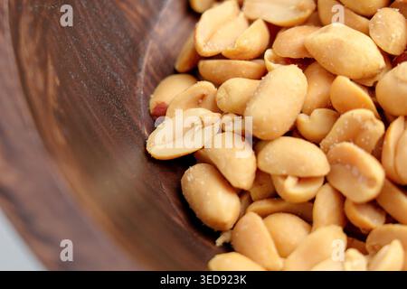 Arachidi salate arrostite in un recipiente rustico di legno. Vista dall'alto. Foto Stock
