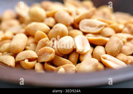 Vista ravvicinata delle arachidi salate arrostite in un recipiente di legno. Chicchi dorati con cristalli di sale marino Foto Stock