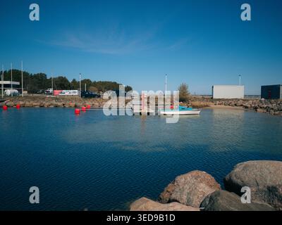 Piccola barca ormeggiata al porto di Lohusalu con calme acque blu e costa rocciosa in una limpida giornata primaverile in Estonia Foto Stock