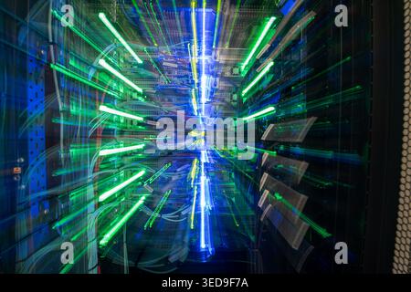 Un display dinamico di vivaci percorsi luminosi blu e verdi cattura l'essenza della tecnologia in una sala server, illustrando connessioni dati e modernità Foto Stock