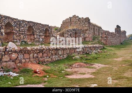 Antiche rovine in pietra con muri erosi e portali ad arco costruiti con pietre e mattoni irregolari. La fortificazione medievale si erge su Foto Stock