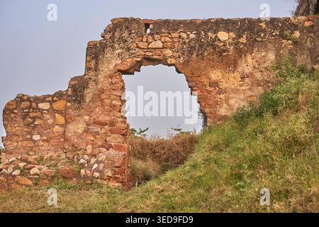Antiche rovine di pietra consumate dalle intemperie con una grande apertura ad arco costruita con pietre irregolari nei toni del marrone, rosso e beige. La deteriorata Foto Stock