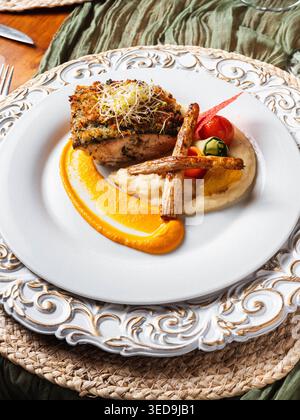 L'elegante piatto può contenere piatti ben placcati. La crosta dorata corona un tenero pezzo di proteina. La scorza d'arancia e la salsa cremosa aggiungono un contrasto vivace. Erbe fresche e. Foto Stock