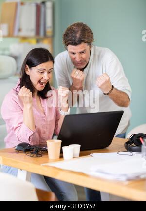 Colleghi felici che condividono il successo guardando lo schermo del notebook Foto Stock