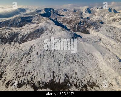 Vista aerea delle cime innevate e delle aspre creste del passo Babusar sotto un cielo luminoso con morbide nuvole Babusar, KPK, Pakistan. Foto Stock