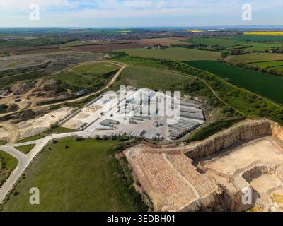 Veduta aerea del sito industriale di Marshalls Maltby con pozzi di cava, depositi di cemento e campi verdi circostanti sotto una S blu chiaro Foto Stock