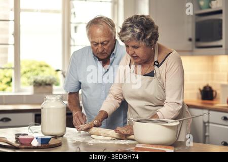 Cottura al forno, coppia felice e senior nella cucina della casa con ingredienti per cena, cena o pasto. Unione, sorriso e anziani con donna dentro Foto Stock