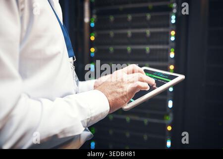 Mani, ingegneri o codici sullo schermo del tablet nella sala server per l'utilizzo della CPU, il monitoraggio delle risorse o il supporto IT. Tecnico, uomo e digitazione della tecnologia nel data center Foto Stock
