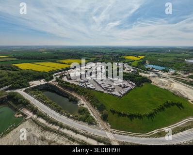 Vista aerea del sito industriale Marshalls Maltby con materiali impilati e pozzi di cava circondati da vibranti campi di colza gialli e verde Foto Stock