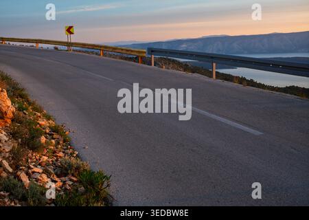 Una spettacolare strada tortuosa sull'isola di Hvar, bagnata dalla luce del sole che sorge Foto Stock