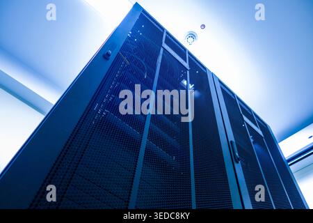 Un'incredibile vista a basso angolo di un server rack in un data center inondata di luce blu. L'immagine cattura la tecnologia e l'infrastruttura in un ambiente moderno Foto Stock