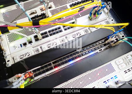 Vista ravvicinata di un server rack con cavi di rete colorati e componenti elettronici, che illustra la moderna tecnologia e i connettori dei data center Foto Stock