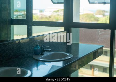 Un bagno luminoso e moderno con un elegante lavandino e una splendida vista dalle grandi finestre, crea un'atmosfera tranquilla e invitante. Foto Stock