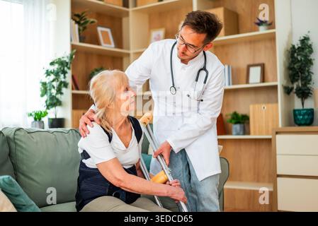 Un medico compassionevole aiuta un paziente in guarigione a riprendersi la mobilità, mentre si prepara a fare passi attenti in casa. Foto Stock