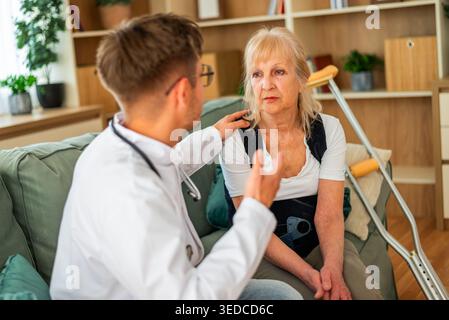 Una donna anziana in riabilitazione è assistita da un professionista medico, evidenziando la cura, il recupero, e supporto di terapia fisica. Foto Stock