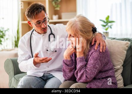 Un medico abbraccia dolcemente una donna anziana, rappresentando compassione e cure incentrate sul paziente. Foto Stock