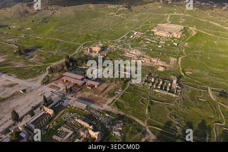 Vista aerea con drone della città antica di Hierapolis e dei travertini di Pamukkale a Denizli, Turchia, teatro romano, colonne antiche e paesaggio UNESCO Foto Stock