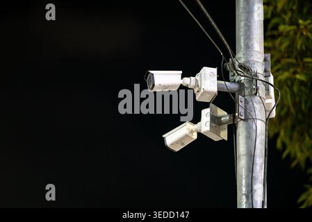 Visione mirata di più telecamere di sicurezza installate su un palo di notte, evidenziando la tecnologia di sorveglianza urbana per la sicurezza e il monitoraggio. Foto Stock