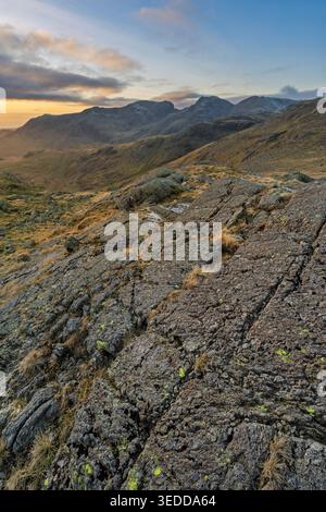 Vista della catena montuosa di Scafell nel Lake District con un'enorme lastra di roccia in primo piano. Foto Stock