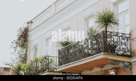 Foto orizzontale di una facciata di un edificio classico rosa con balconi ornati in ferro battuto Foto Stock