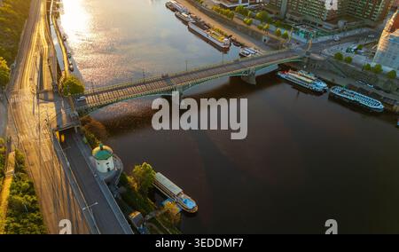 Vista aerea del Ponte Cech che attraversa il fiume Moldava con barche ormeggiate e architettura storica durante l'ora d'oro a Praga, Praga, Czechia. Foto Stock