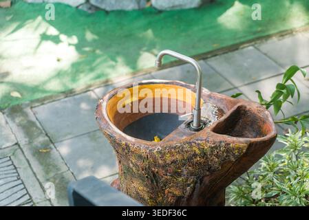 Questo esclusivo lavandino in legno fonde un design moderno con la natura, con un elegante rubinetto e una finitura rustica in legno. Perfetto per spazi esterni e giardini. Foto Stock