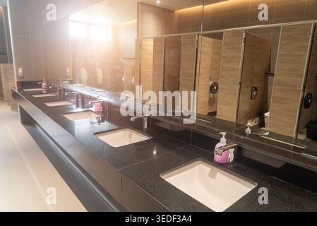 Questa immagine presenta un bagno elegante e moderno con un lavandino elegante, lavandini multipli e linee pulite. L'uso efficace dell'illuminazione migliora il sovraccarico Foto Stock
