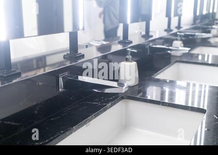 Un moderno lavandino del bagno con eleganti superfici in marmo, eleganti lavandini e illuminazione ambientale, ideale per mostrare il design e l'igiene del bagno di lusso Foto Stock