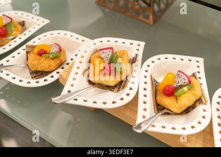Le vivaci crostate di frutta sono splendidamente disposte su eleganti piatti da dessert. Ogni crostata presenta una combinazione di frutta fresca, aggiungendo colore e sapore. Foto Stock