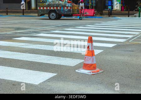 Il cono di sicurezza stradale si fissa su una traversa con sfondi in asfalto Foto Stock
