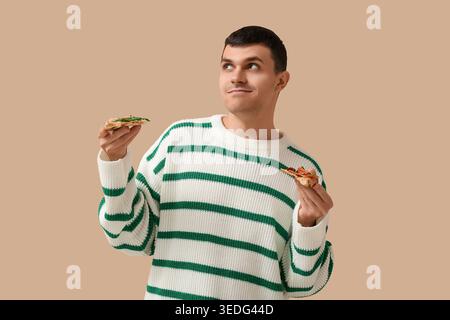 Giovane con pezzi di gustosa pizza su sfondo beige Foto Stock
