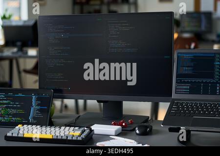 Primo piano di una workstation di codifica che visualizza lo sviluppo software su più schermi, supporta programmazione, sicurezza informatica, ingegneria dei dati o marketing dei servizi IT Foto Stock