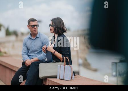 Due persone d'affari sedute sul lungomare che hanno una conversazione professionale durante una pausa Foto Stock