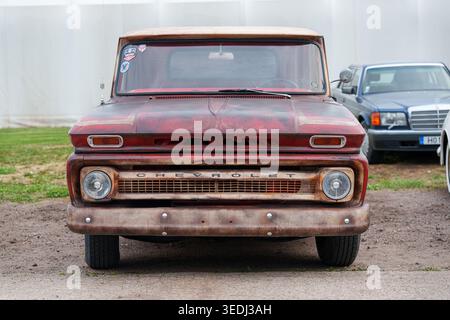 Vista frontale di un pick-up Chevrolet C10 d'epoca con vernice patina rossa resistente agli agenti atmosferici, classico design retro americano parcheggiato all'aperto in una mostra di automobili Foto Stock