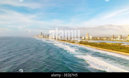 Una vista panoramica aerea che cattura il vibrante skyline della Gold Coast che si estende lungo l'Oceano Pacifico, caratterizzato da onde bianche incontaminate e rigogliosa costa Foto Stock