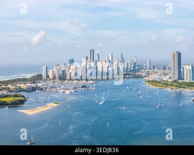Una vista aerea mozzafiato che cattura l'iconico skyline della Gold Coast, i vivaci corsi d'acqua pieni di barche a vela e la tranquilla bellezza costiera su un sole Foto Stock