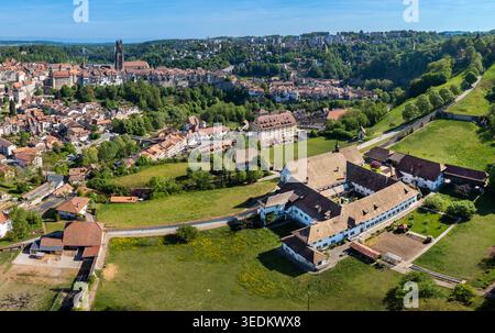 Veduta aerea del Monastere de Montorge circondato da prati verdi con la storica città di Friburgo e la sua cattedrale sullo sfondo sotto una cl Foto Stock
