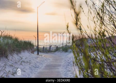 Calma sul mare Baltico su una passerella di legno attraverso dune di sabbia verso il Mar Baltico al tramonto a Liepaja. Viaggio, atmosfera costiera e bassa stagione Foto Stock