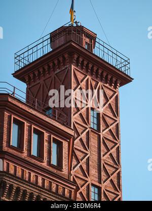 Vecchia torre di guardia contro un cielo limpido. Torre dell'acqua del tardo XIX secolo con cornici in legno dipinte di rosso e piattaforma di osservazione. Foto Stock