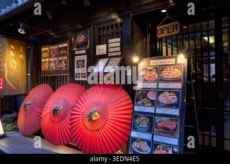 Ombrelloni rossi all'ingresso di un ristorante a Pontocho, uno stretto e suggestivo vicolo fiancheggiato da vecchi e pittoreschi edifici a Kyoto, in Giappone. Foto Stock
