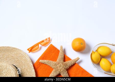 Telo da mare, cappello, occhiali da sole, stelle marine e frutta su sfondo bianco, piatto. Spazio per il testo Foto Stock