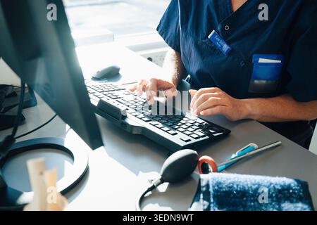 Intersezione di donna medico esperto di digitazione su tastiera durante il lavoro in ufficio ospedaliero Foto Stock